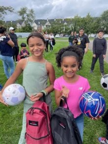 two young girls pose with soccer balls