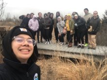 smiling student and others posed behind in grassy environment